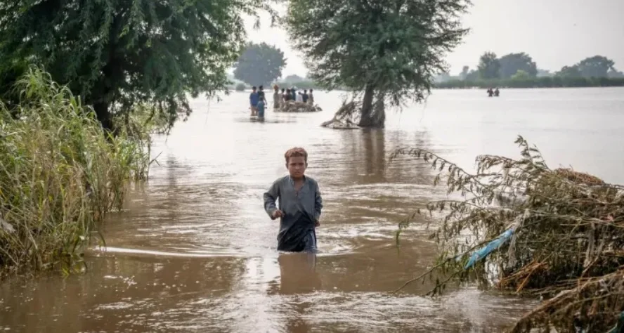 Un niño camina en medio de una calle inundada | Foto de Unicef